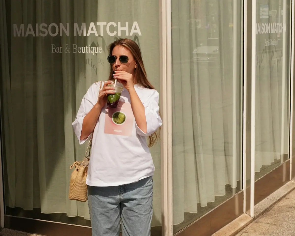 Woman enjoys a matcha drink outside a shop.