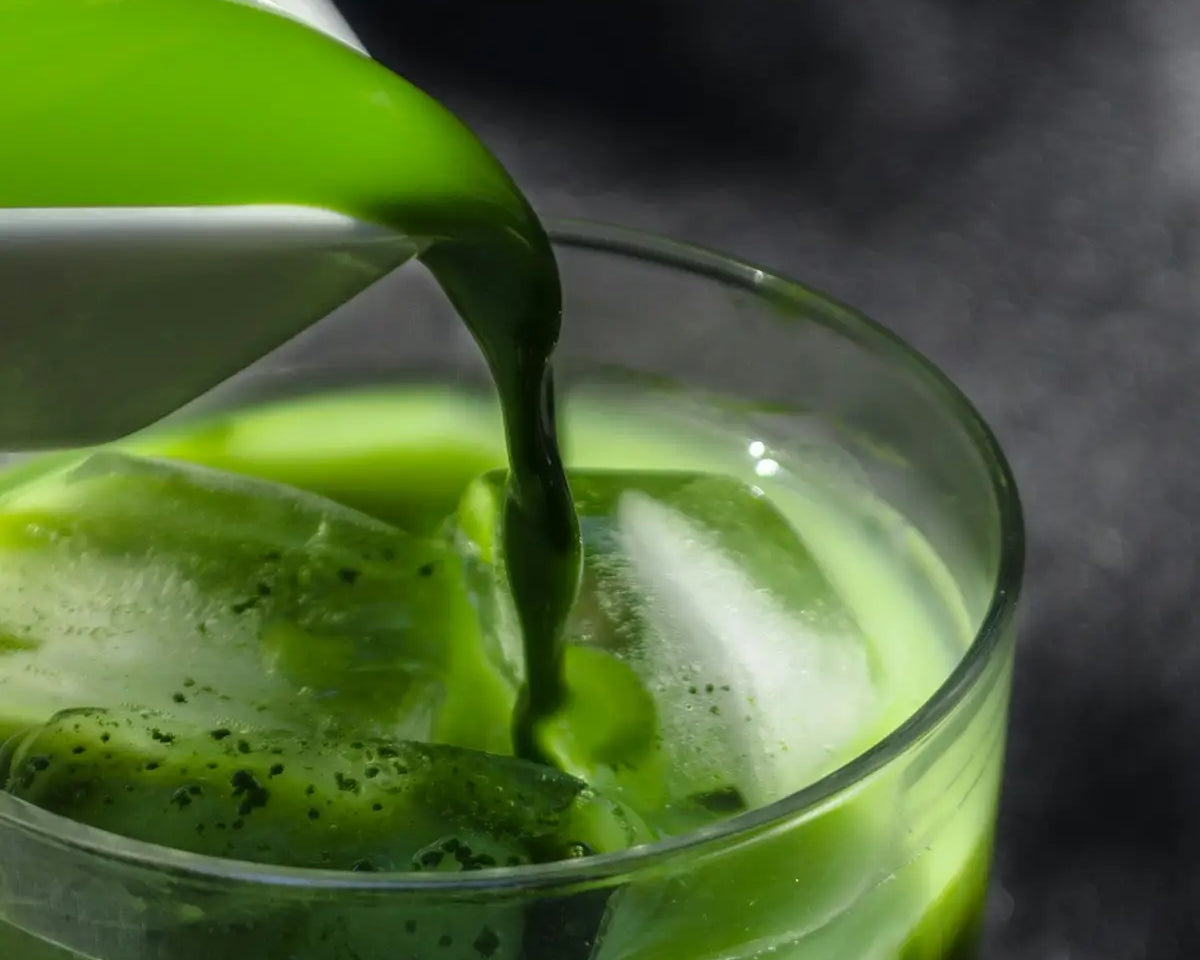 a pitcher pouring green liquid into a glass
