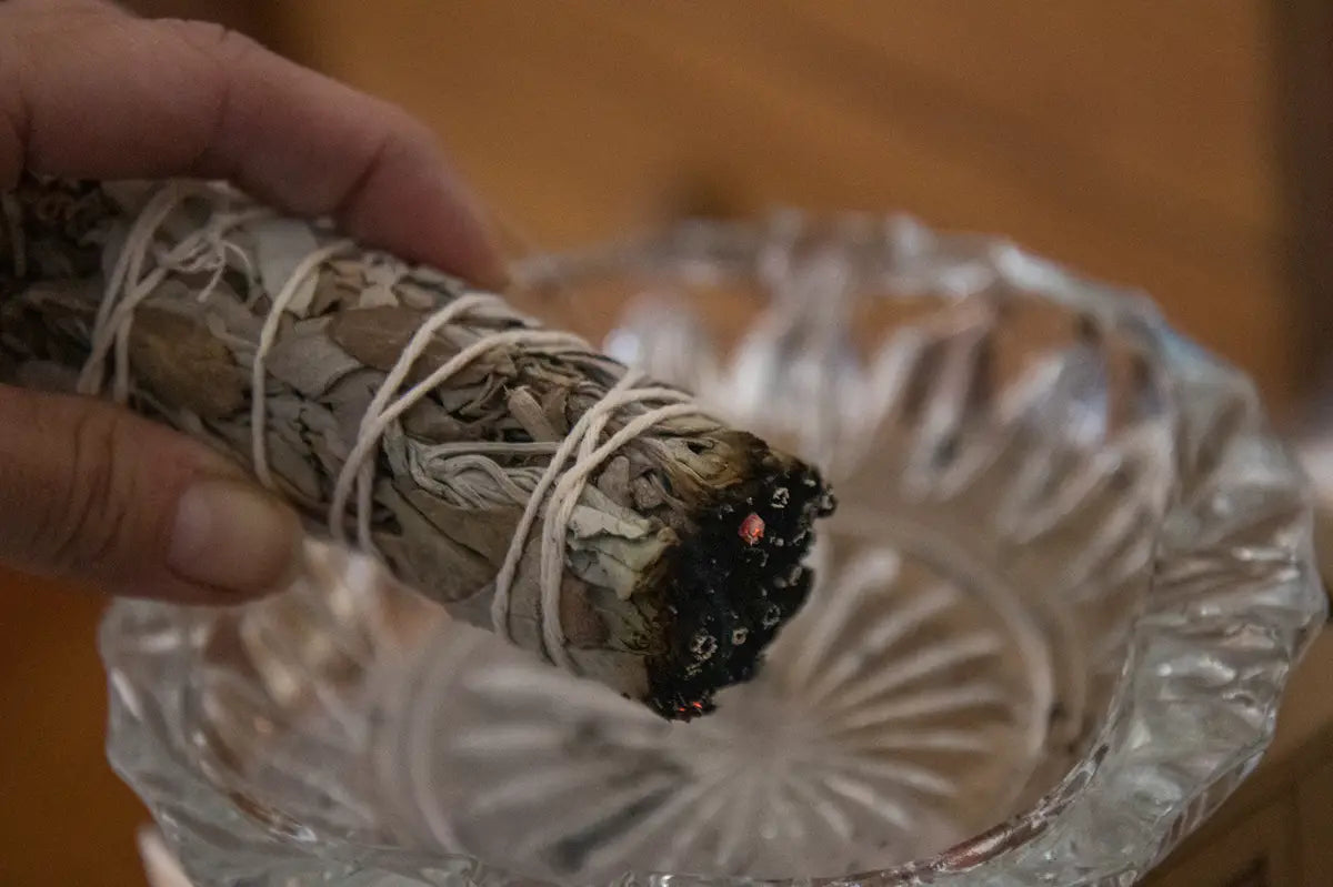 smudge stick held over glass smudge bowl
