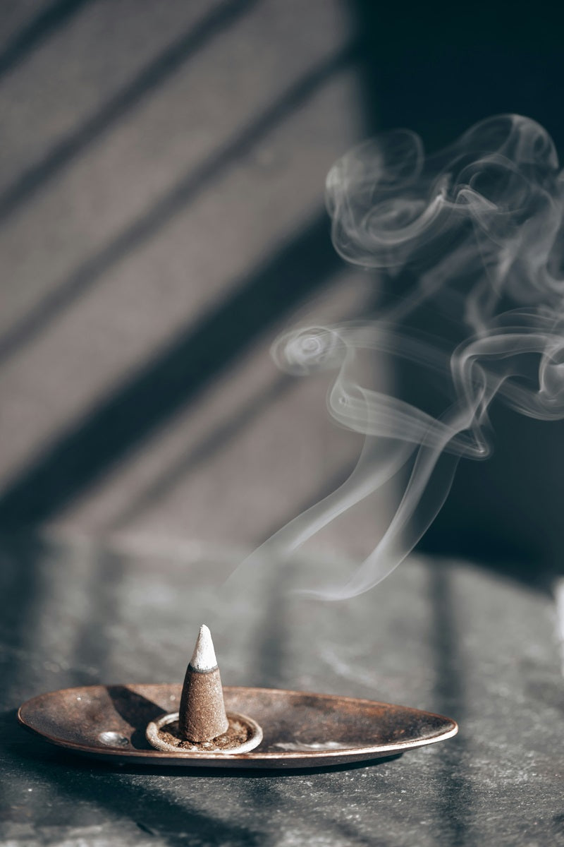 burning incense cone in tray with fragrant smoke