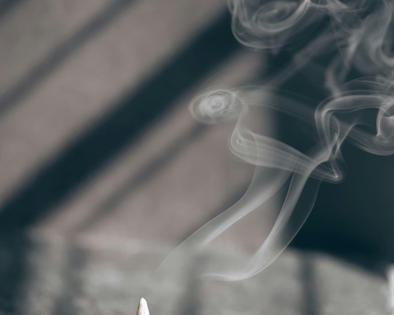 burning incense cone in tray with fragrant smoke