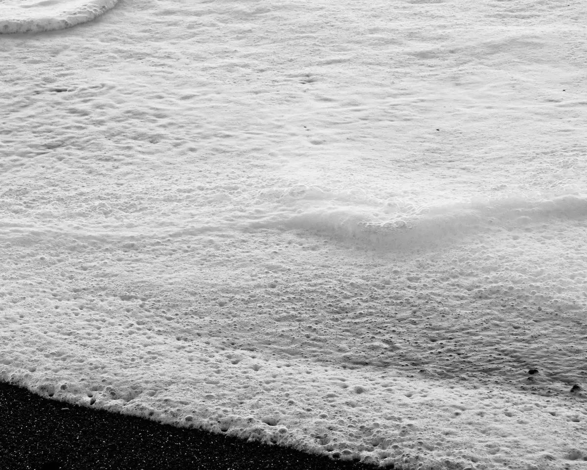 Foamy ocean wave washing over dark sand