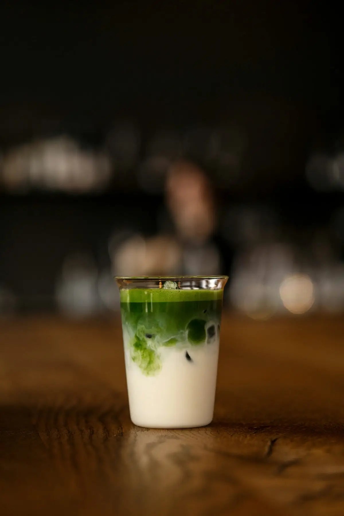 a shot glass filled with green liquid on top of a wooden table