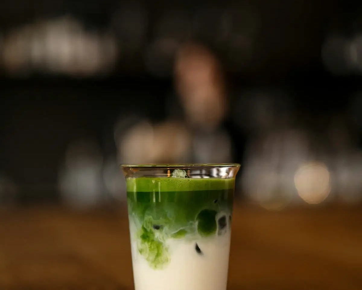 a shot glass filled with green liquid on top of a wooden table