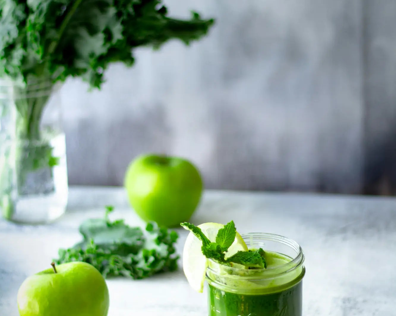 green juice in cup next to apples and kale