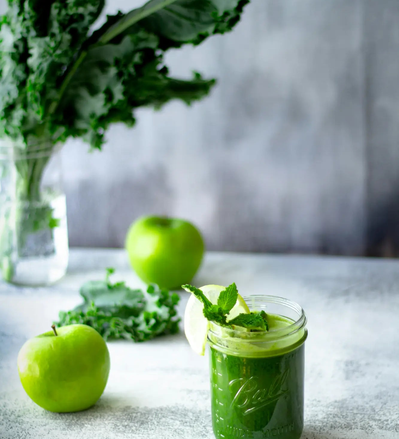 green juice in cup next to apples and kale