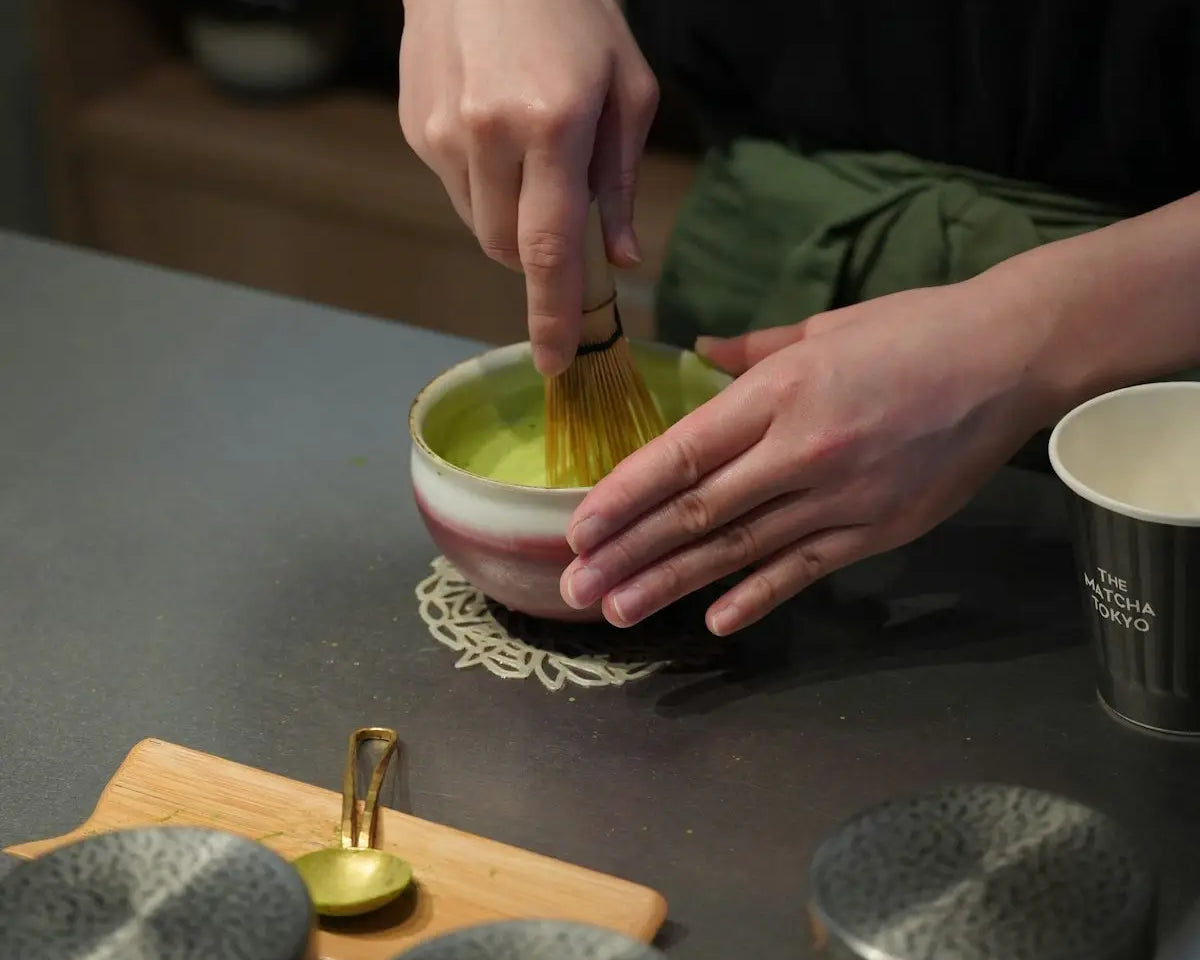 Someone is whisking matcha tea in a bowl.