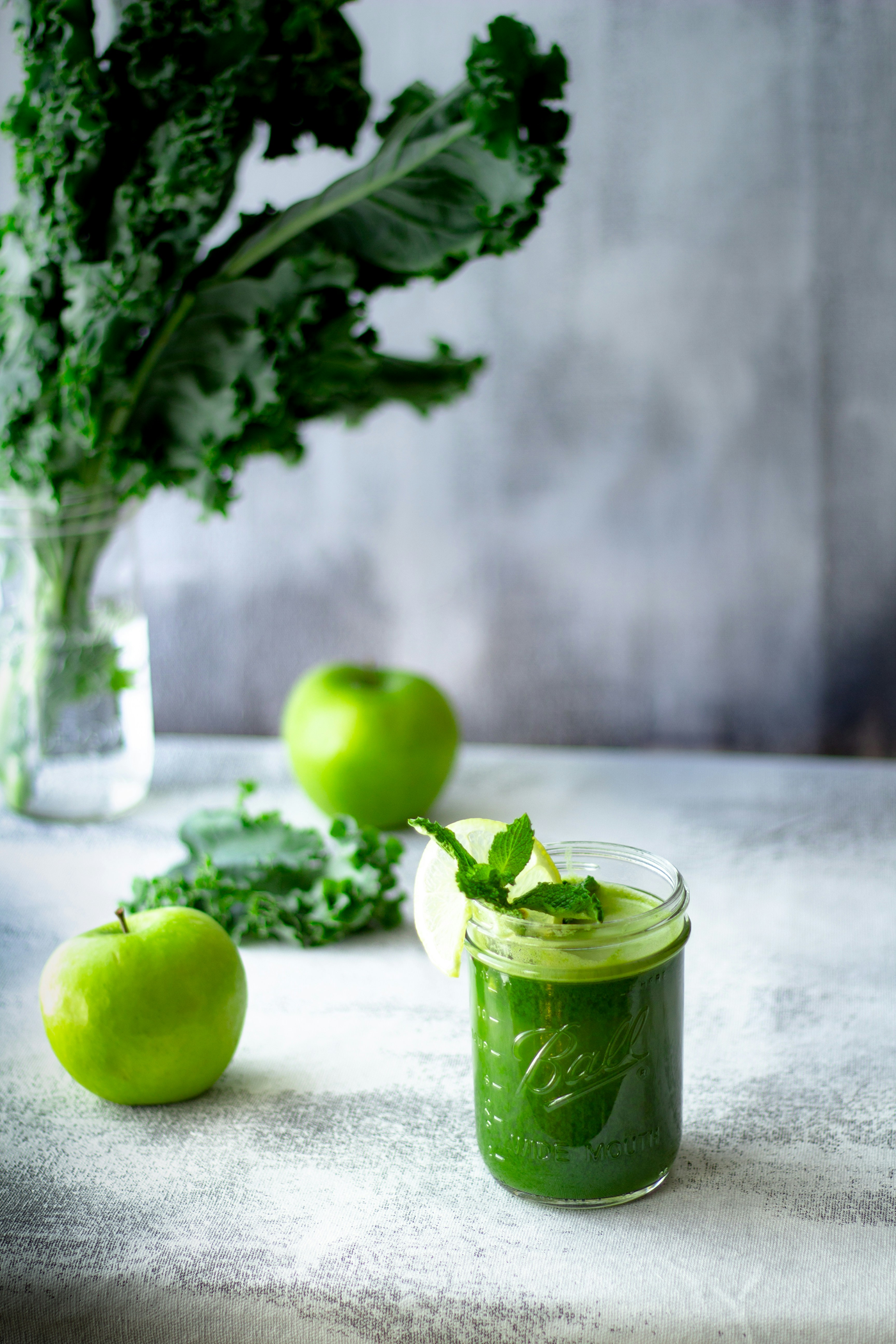 green juice in cup next to apples and kale