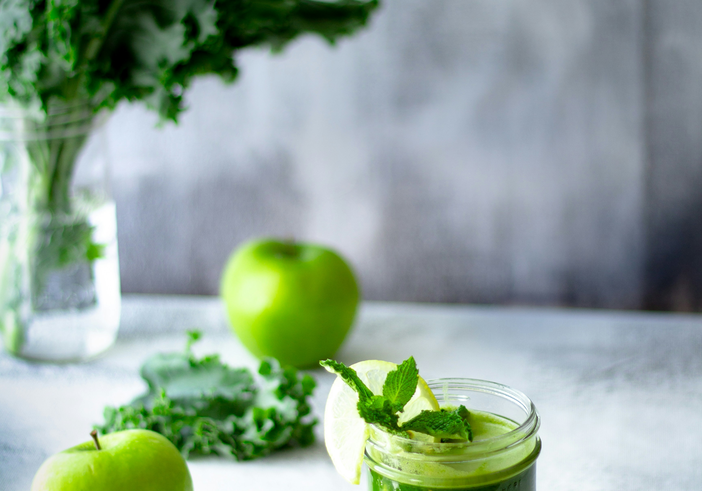 green juice in cup next to apples and kale