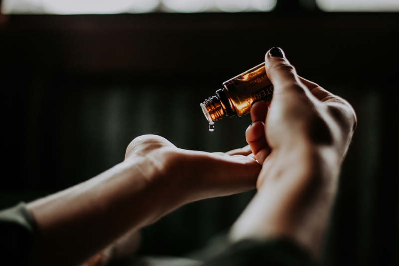 dropping essential oil onto hand from bottle