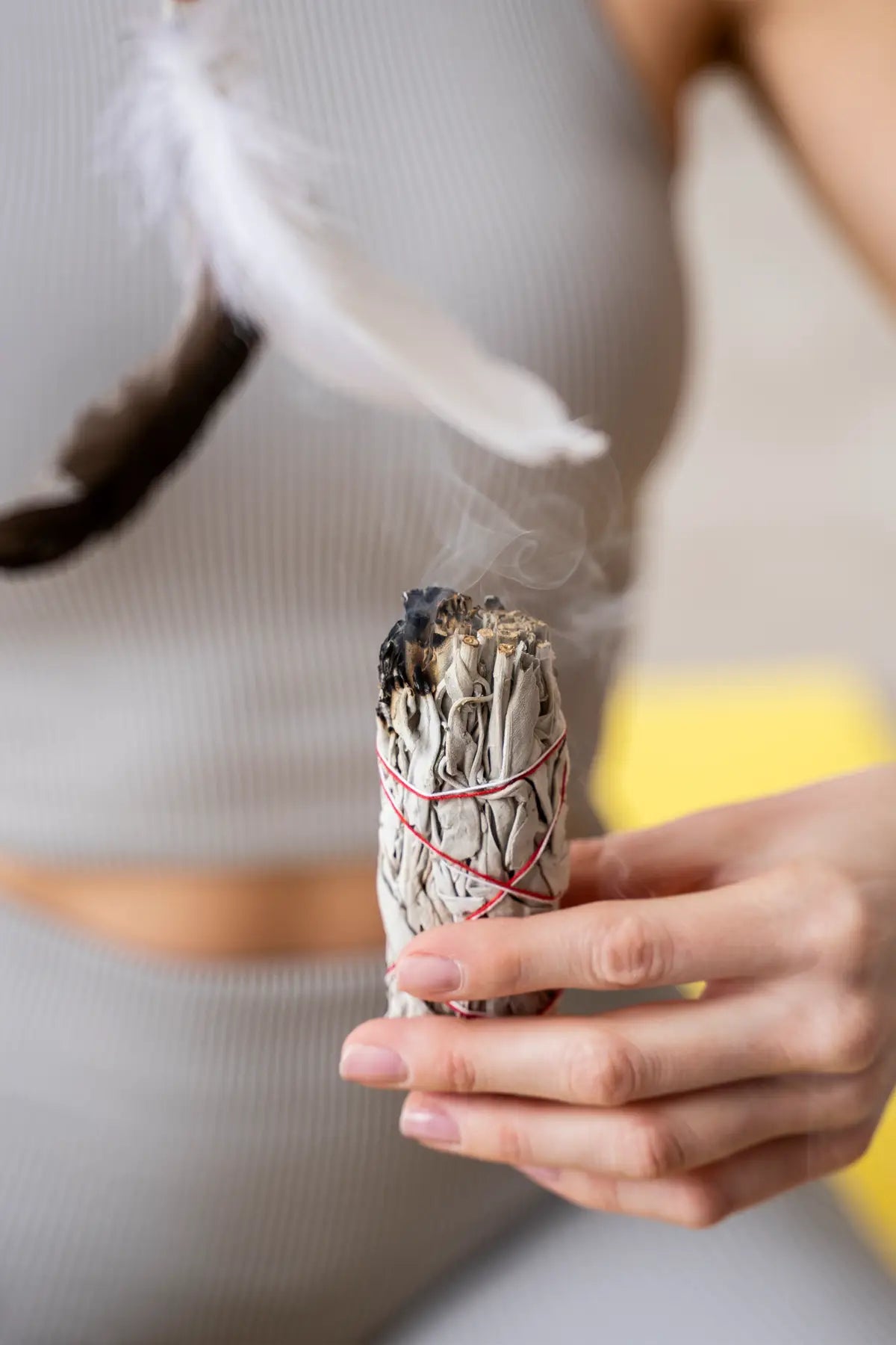 woman smudging with white sage and feathers
