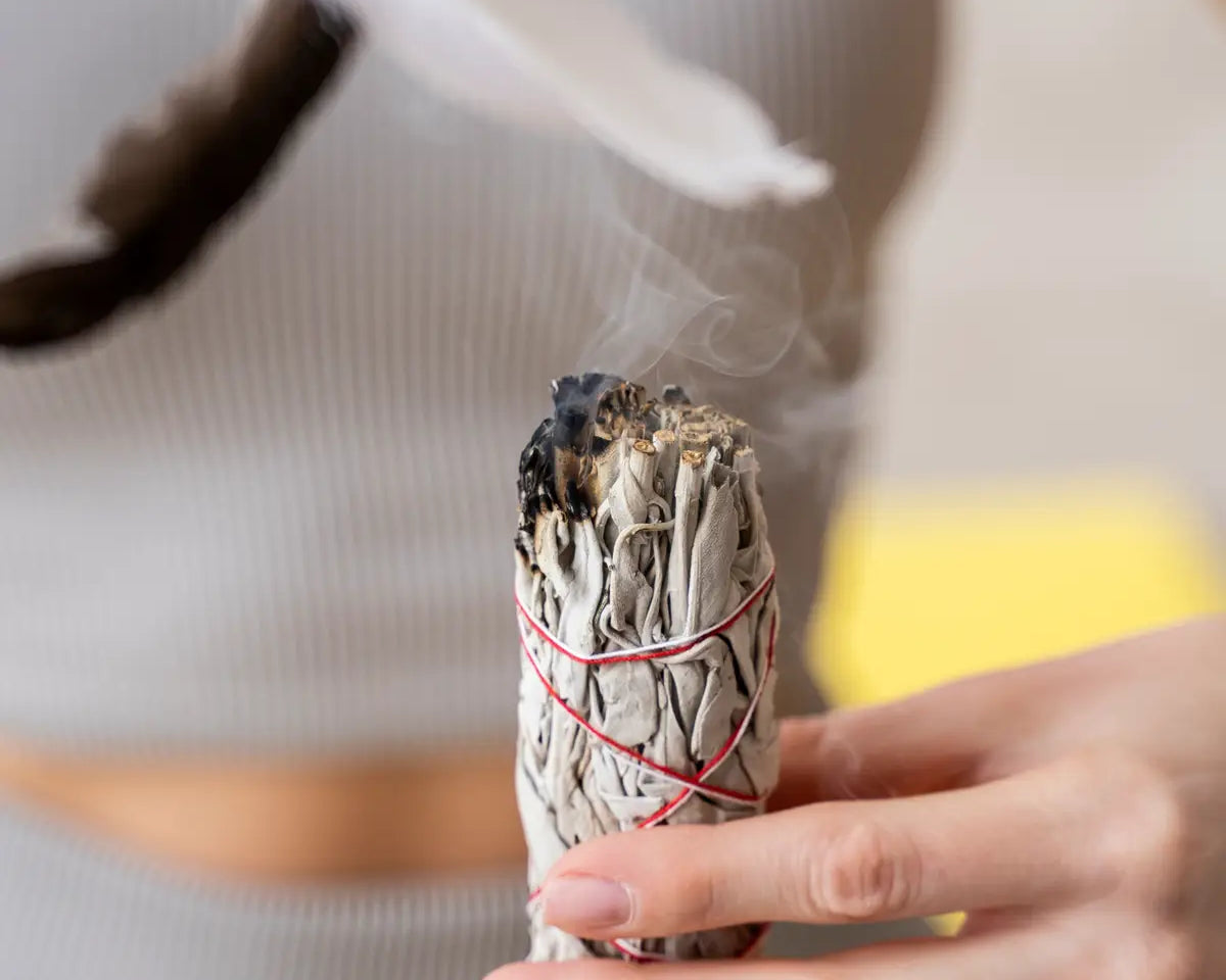 woman smudging with white sage and feathers