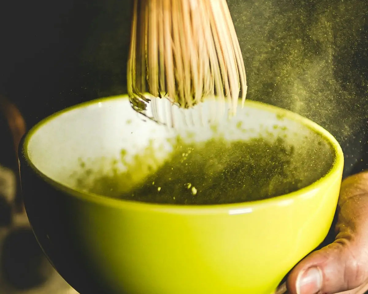 person holding yellow ceramic bowl with green soup