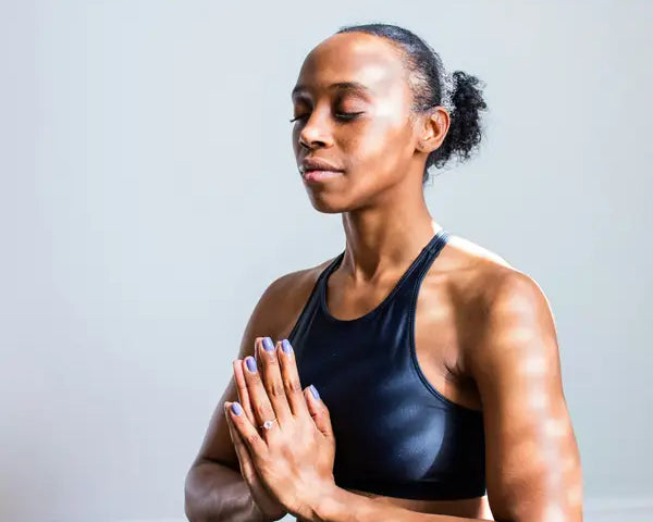 woman sitting meditating with eyes closed and hands in prayer