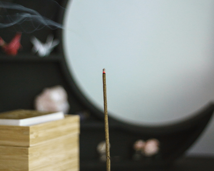 burning incense stick in front of moon