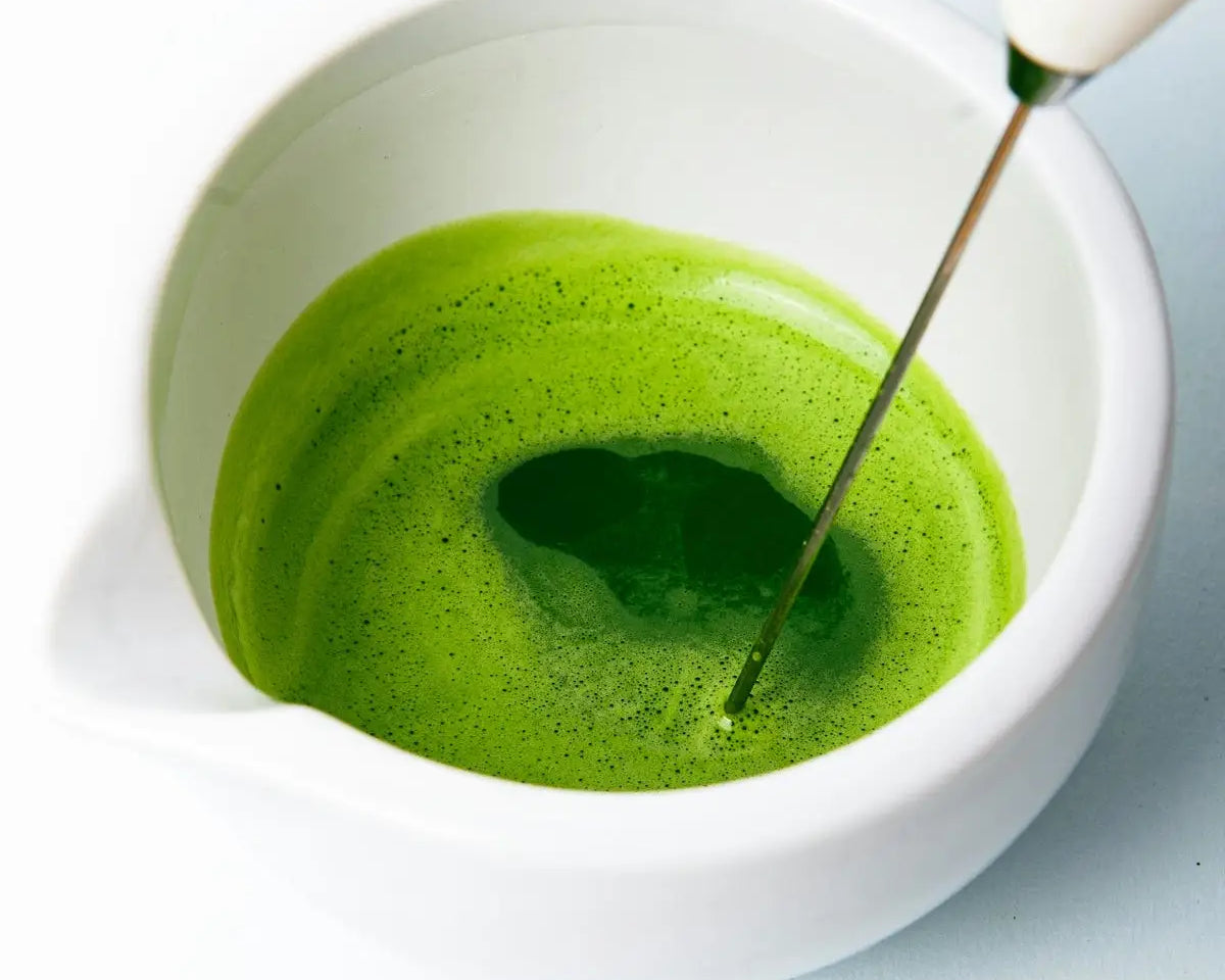 a green liquid in a white bowl with a spoon