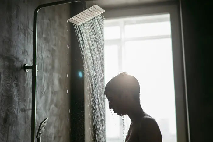 person standing under running shower water