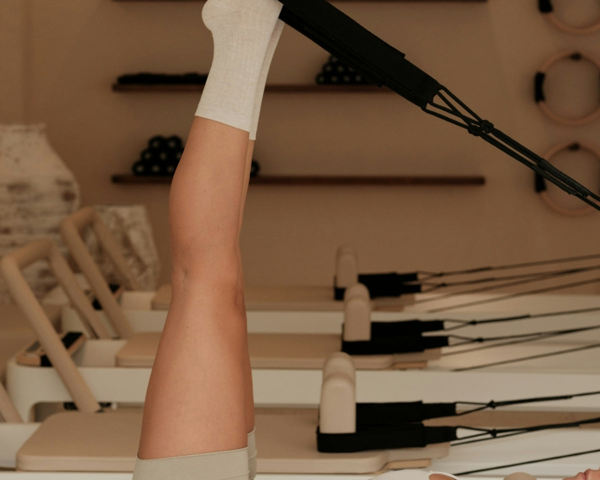Woman does pilates exercise on a reformer machine.