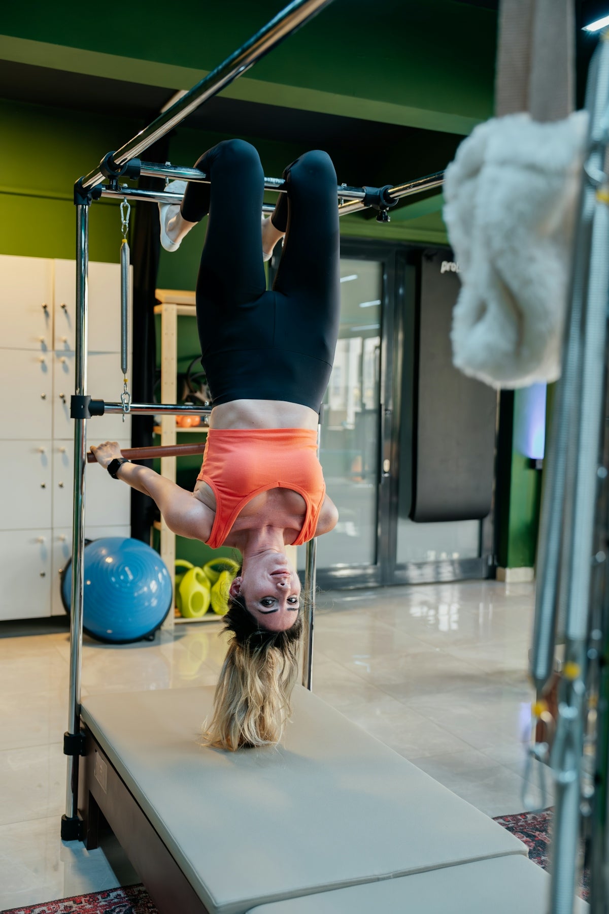 Woman doing pilates exercise upside down on a reformer.