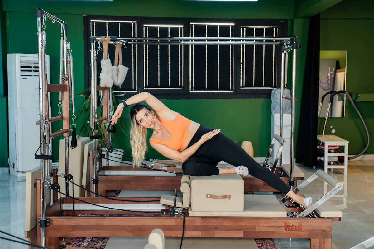 Woman does pilates exercises on a reformer machine.