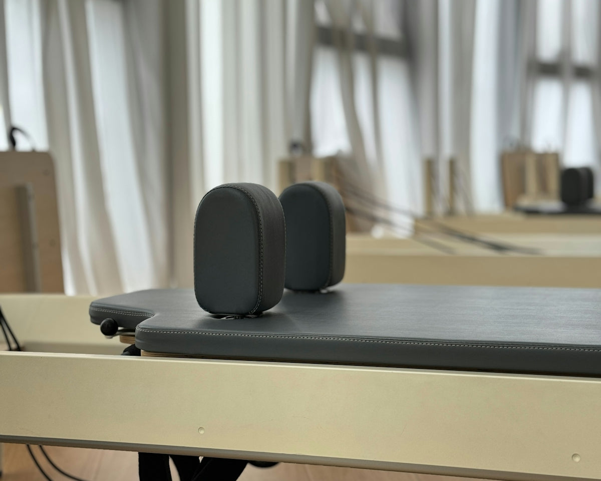 Pilates reformer with padded headrest and straps.