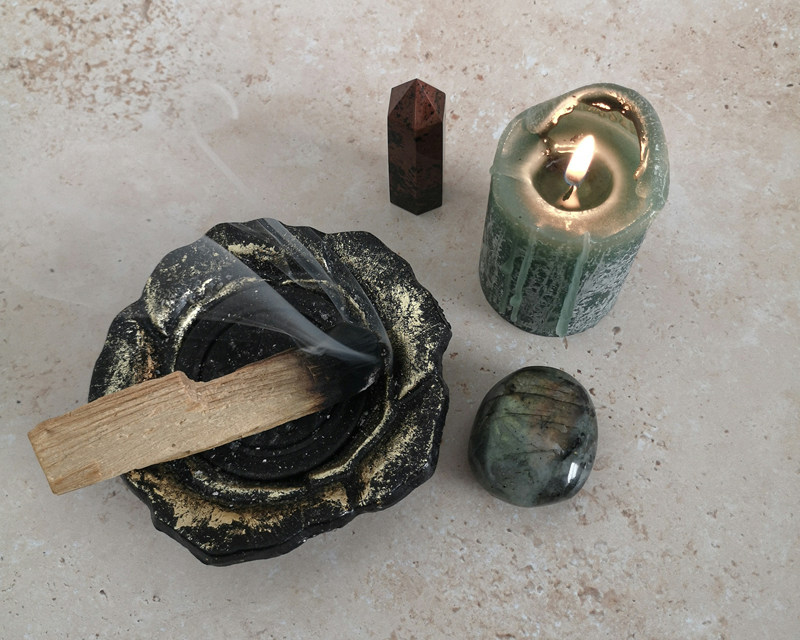 burning palo santo stick candle and crystals