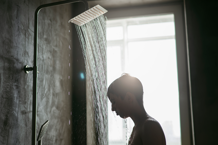 person standing under running shower water