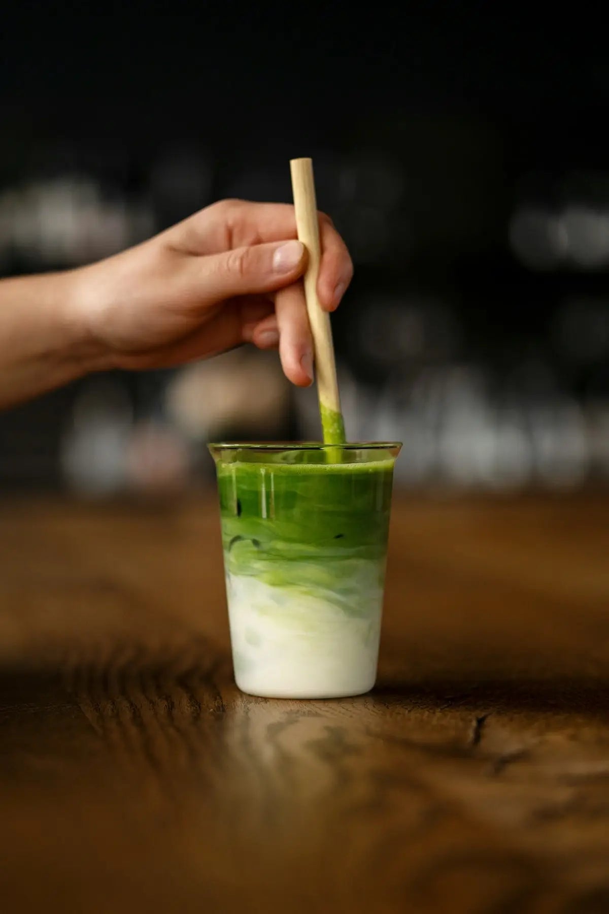 a hand holding a wooden stick over a green drink