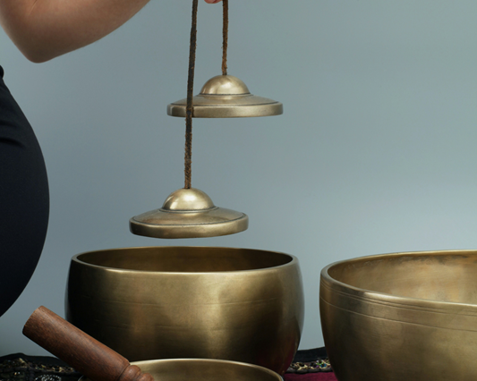 woman holding tibetan chime above a range of tibetan singing bowls