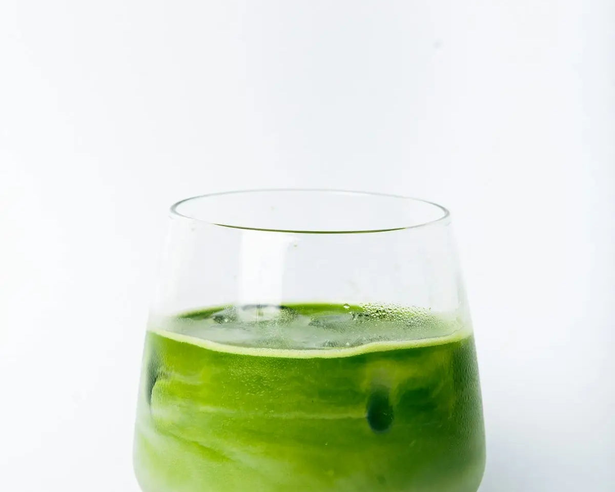 a green liquid in a glass with a wooden coaster