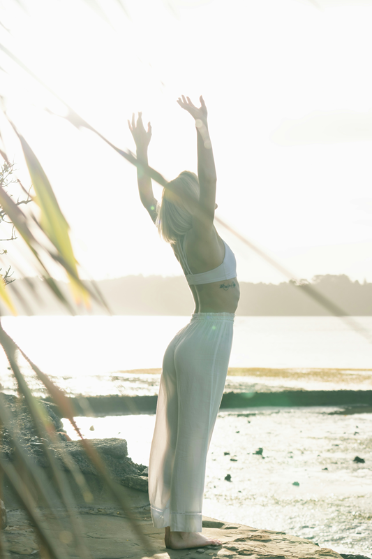 woman doing sun salutation at rockpools