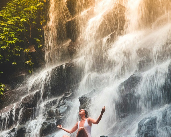 woman meditation in front of waterfall