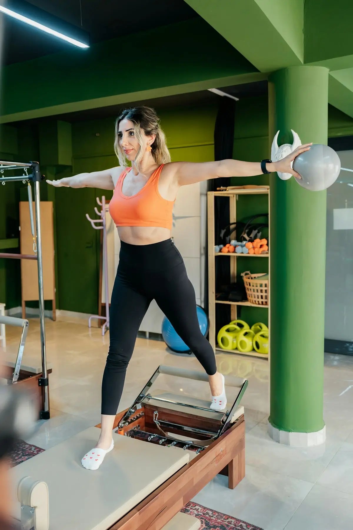 Woman exercises on a pilates machine with a ball