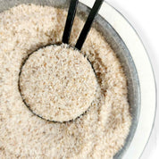 Bowl of uncooked white rice with a black scoop alongside Organic Psyllium Husk Powder