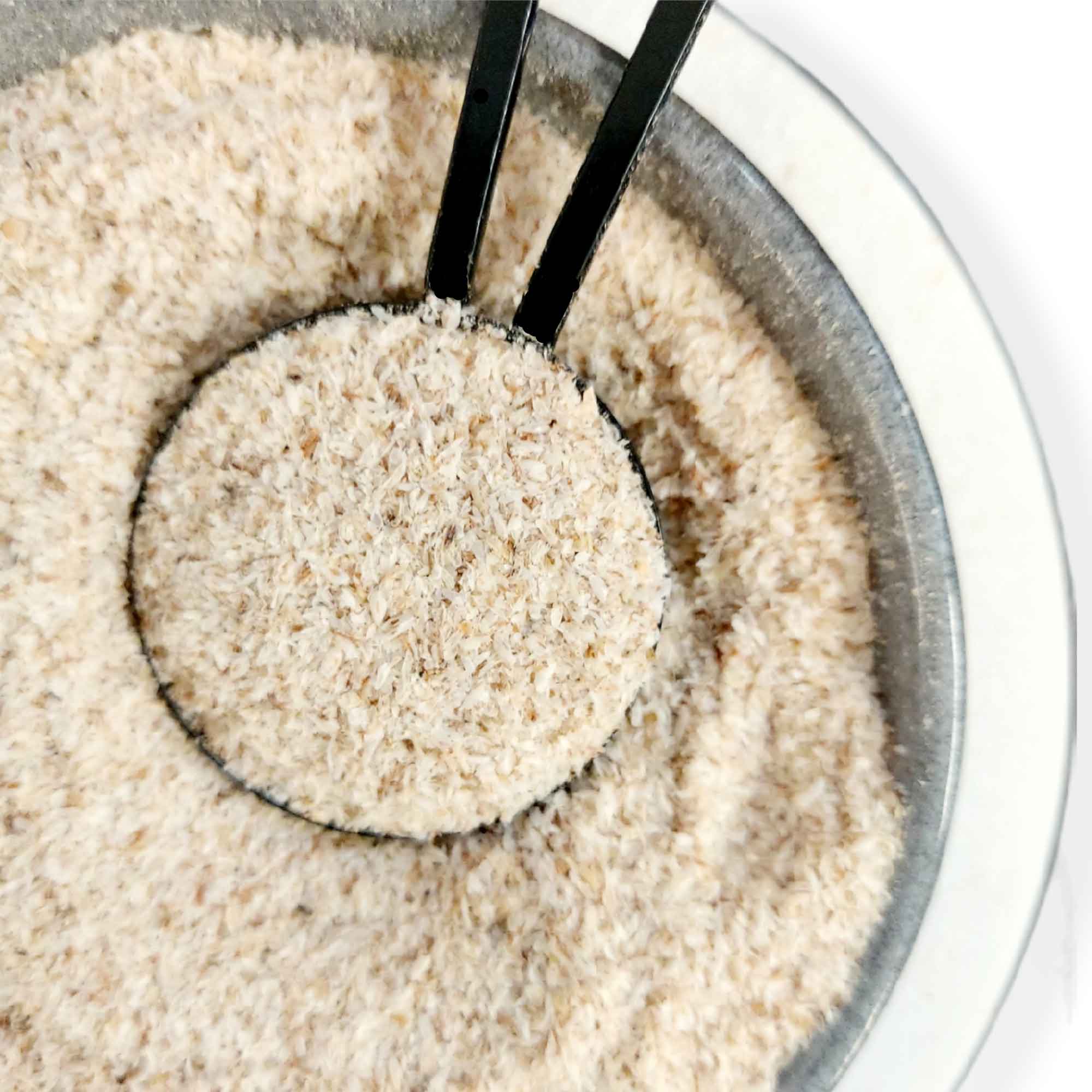 Bowl of uncooked white rice with black tongs next to Organic Psyllium Husk Powder Bag