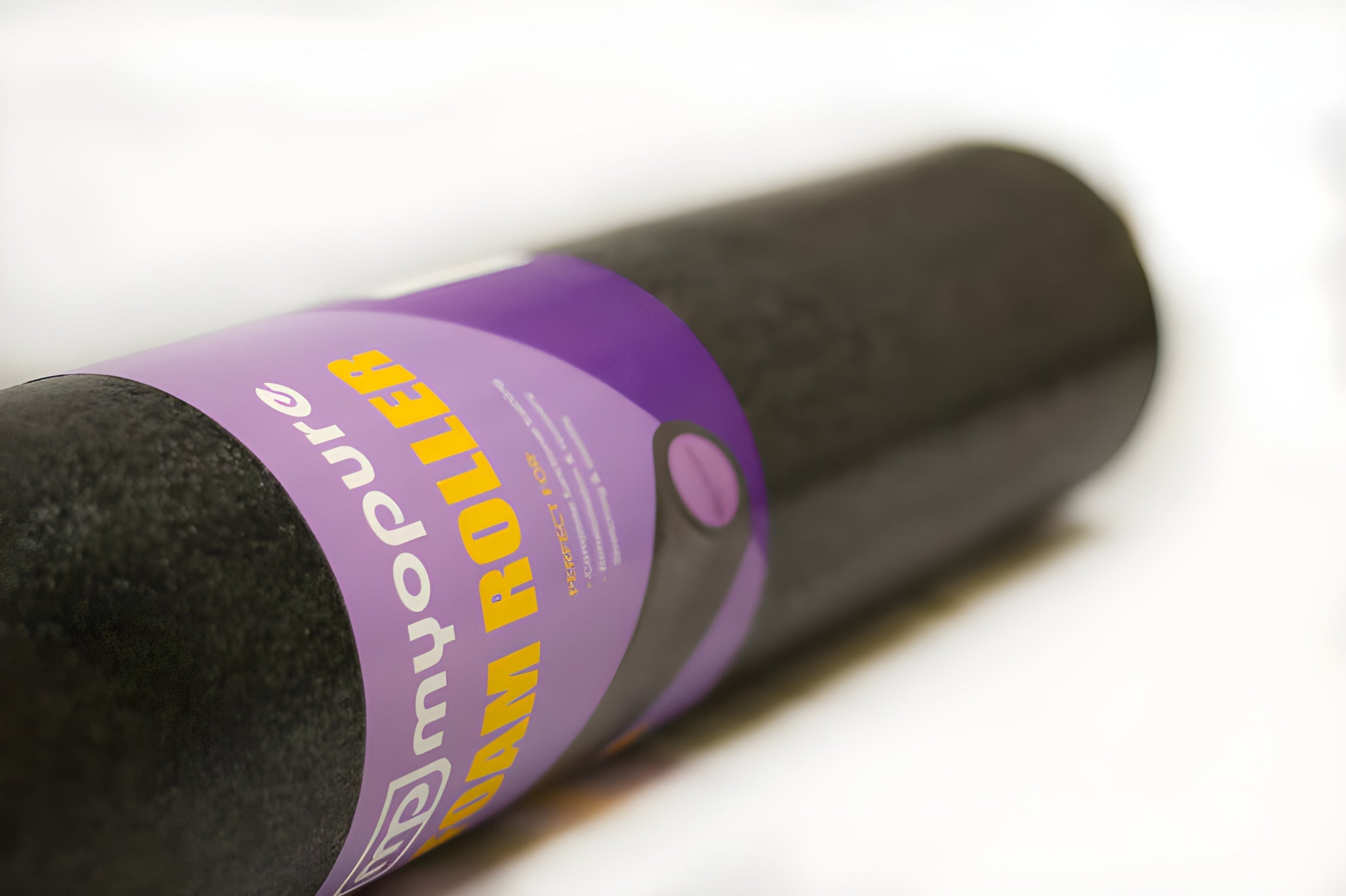 Black cylindrical Yoga Foam Roller with purple label for Pilates exercise and home massage