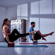 Two people doing synchronized leg raises on Adidas Eco Yoga mats with Eco Yoga Block