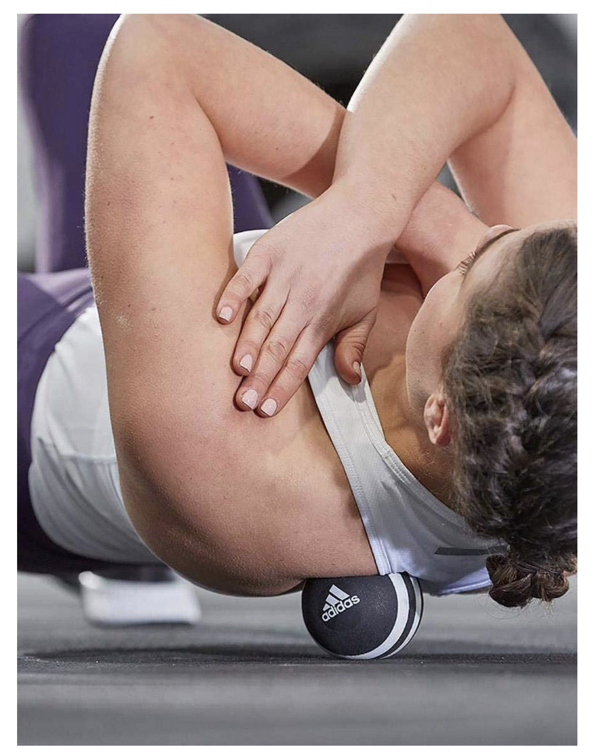 Foam roller massages shoulder muscles during recovery with Adidas Massage Ball Gym