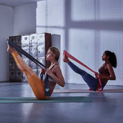 Two people using Adidas Pilates Bands for resistance exercises on yoga mats