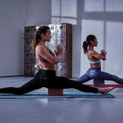 Two people in synchronized yoga splits with Adidas Cork Yoga Blocks on exercise mats