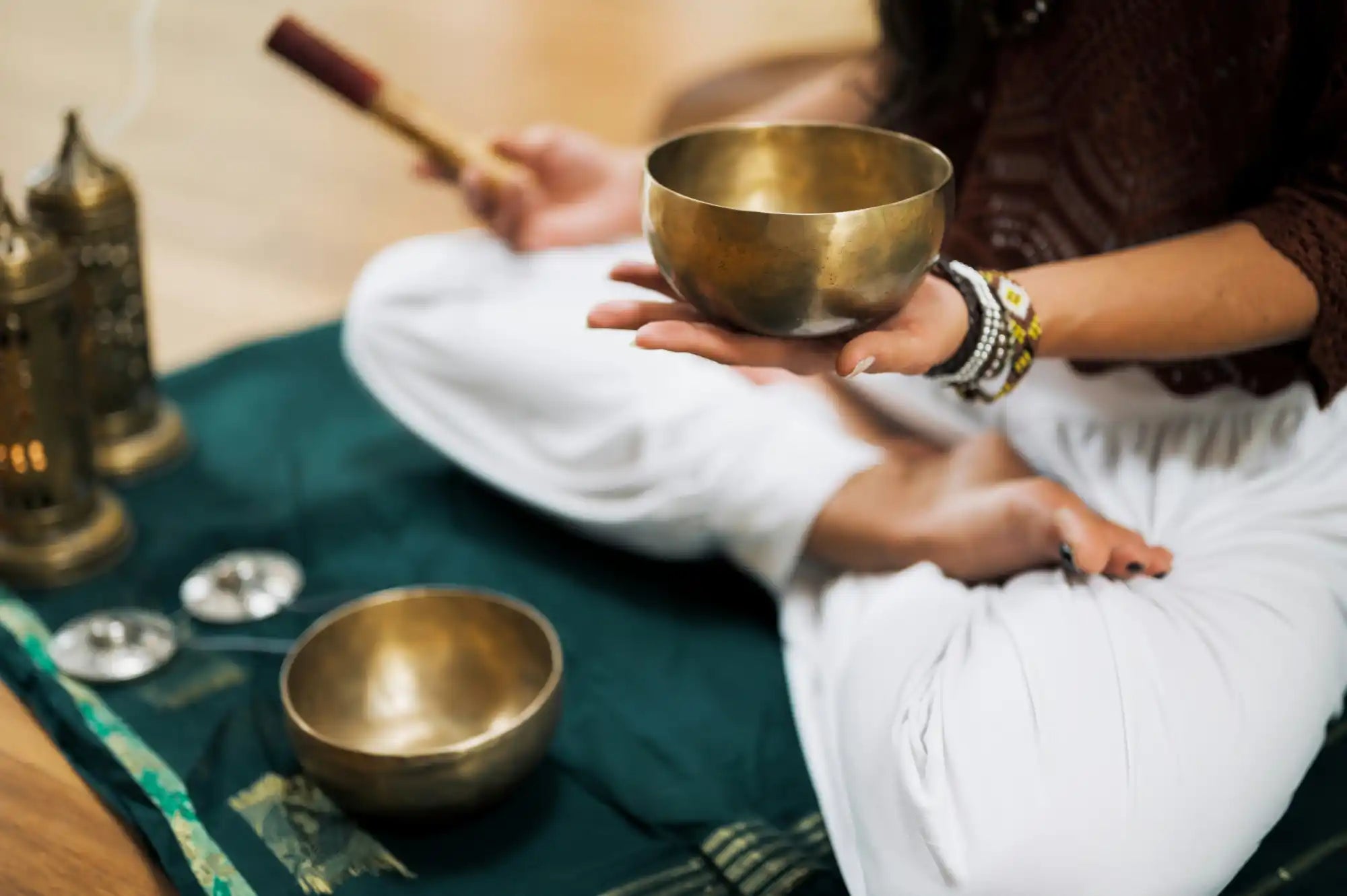 Brass Tibetan singing bowl held in meditation pose with mallet.