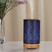 Decorative ultrasonic aroma diffuser with blue metal cover and wood grain base emitting vapor