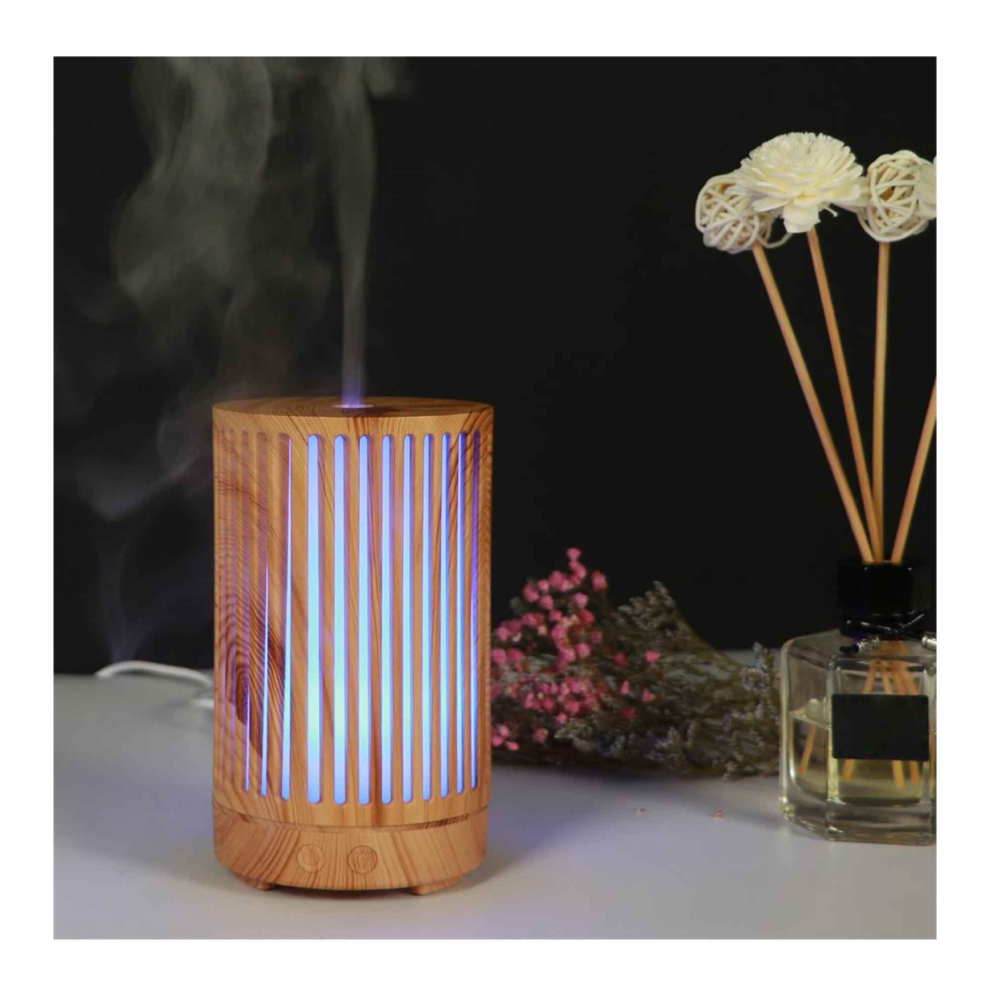 Cylindrical wooden diffuser with light wood grain emitting blue steam and ultrasonic aroma