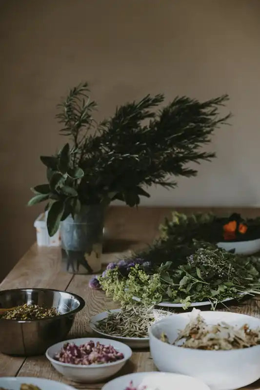 Fresh herbs and ingredients arranged on a wooden surface with bowls.