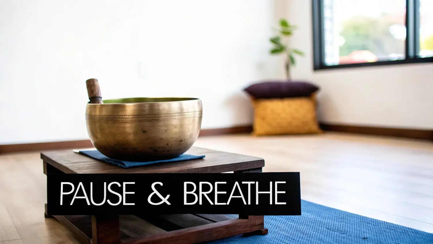 A serene meditation space with a singing bowl, mallet, and 'Pause & Breathe' sign on a yoga mat.