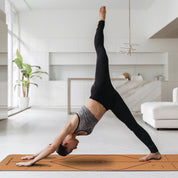 Three-legged downward dog pose on Powertrain Cork Yoga Mat for home gym pilates