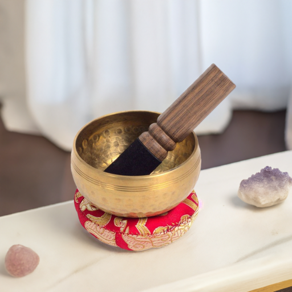 small Tibetan singing bowl on cushion with crystals and mallet